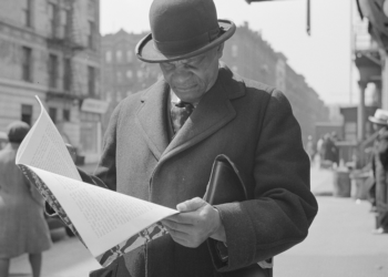 New York, New York. A. Marcus Garveyite reading the OWI (Office of War Information) publication Negroes and the War, April 1943. Library of Congress Prints and Photographs Division, Washington, D.C. 20540, USA. OWI was the Executive Branch agency under the control of the White House. Its Overseas Division produced World War II shortwave radio broadcasts, which were later named the Voice of America (VOA).