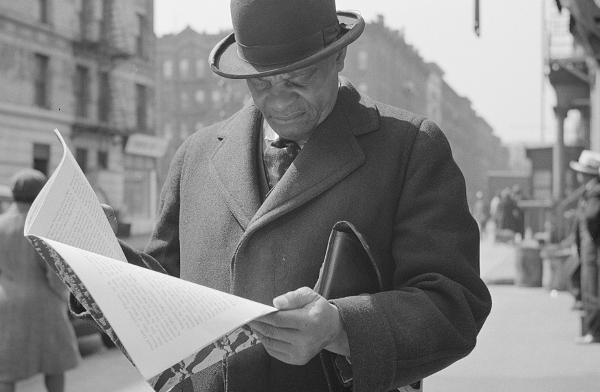 New York, New York. A. Marcus Garveyite reading the OWI (Office of War Information) publication Negroes and the War, April 1943. Library of Congress Prints and Photographs Division, Washington, D.C. 20540, USA. OWI was the Executive Branch agency under the control of the White House. Its Overseas Division produced World War II shortwave radio broadcasts, which were later named the Voice of America (VOA).